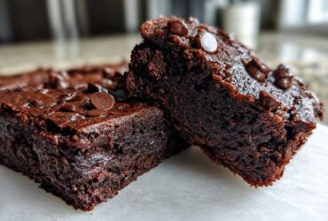 Close-up of two rich, fudgy sweet potato brownies topped with chocolate chips.