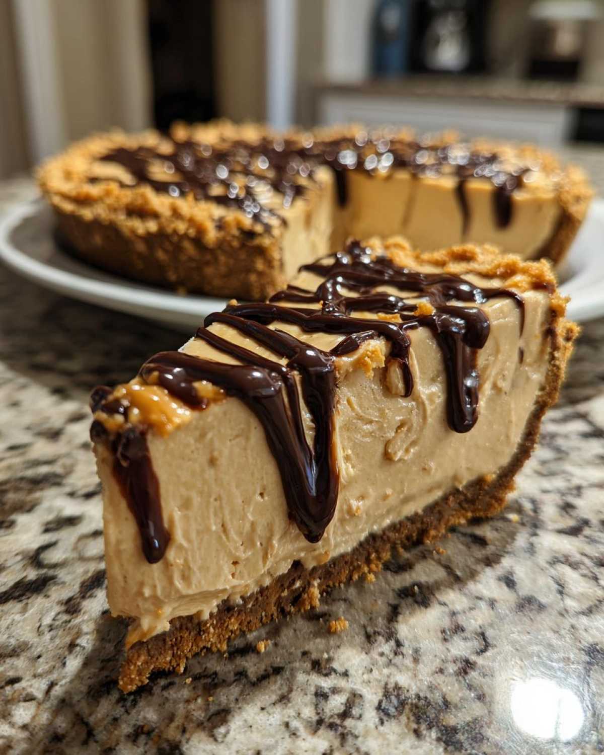 A close-up slice of creamy no-bake peanut butter pie topped with rich chocolate syrup drizzle.