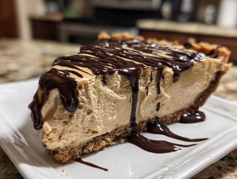 A thick slice of creamy no-bake peanut butter pie on a white plate, topped with rich chocolate syrup drizzle.