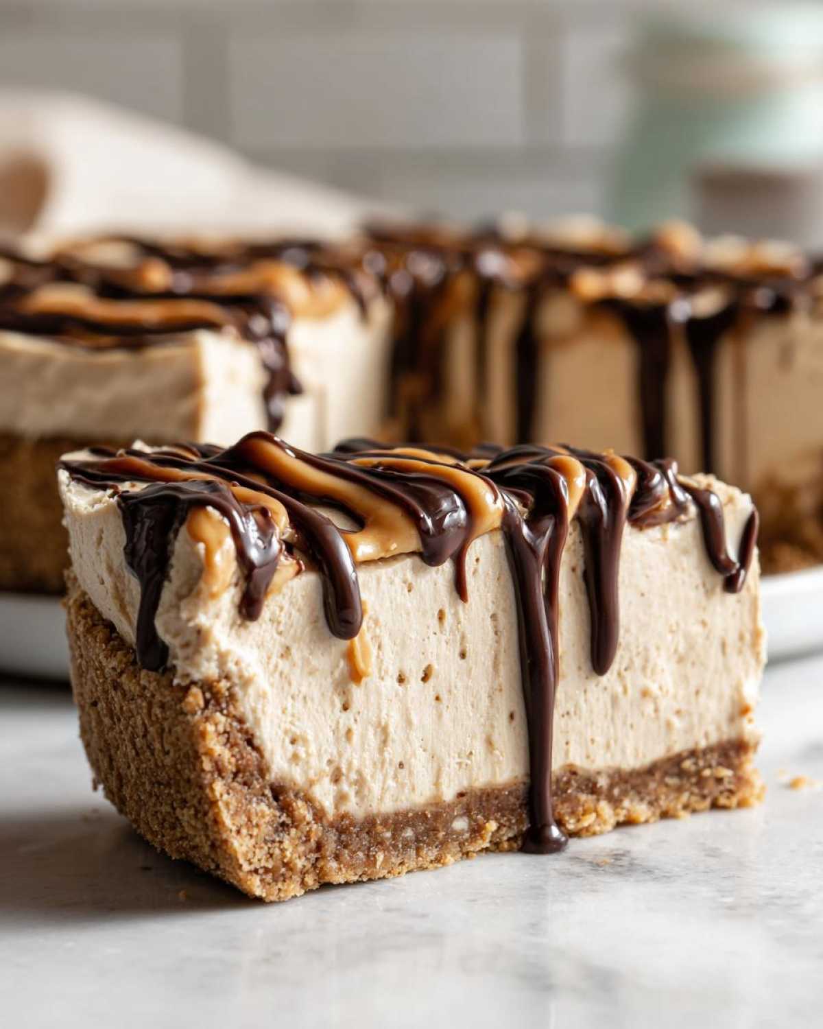 A thick slice of no-bake peanut butter pie with a graham cracker crust, topped with drizzled chocolate and peanut butter sauce.