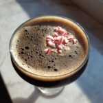 Overhead view of a rich, dark peppermint espresso martini topped with crushed red and white candy canes.
