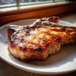 A thick, bone-in pork chop glistening with a caramelized glaze, ready to eat after using the marinade for pork chops.