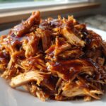 Close-up of moist, shredded crockpot teriyaki chicken generously coated in a thick, glossy teriyaki sauce.