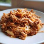 Close-up of tender, shredded pork and sauerkraut mixture served on a white plate, ready for an 8-hour dinner.