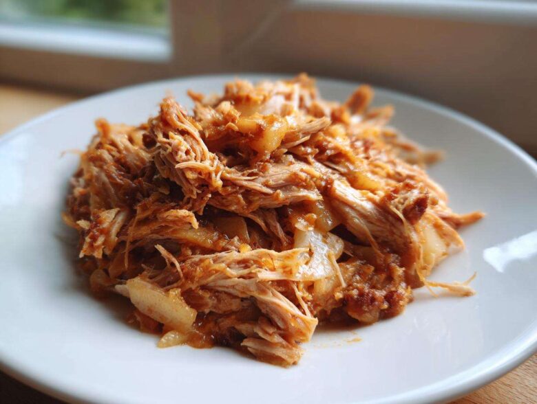Close-up of tender, shredded pork and sauerkraut mixture served on a white plate, ready for an 8-hour dinner.