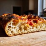 Close-up cross-section showing the airy, open crumb structure of sourdough discard pizza dough with tomato sauce.