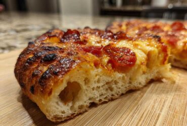 Close-up of a thick slice of pepperoni pizza showing the airy crumb structure of sourdough discard pizza dough.