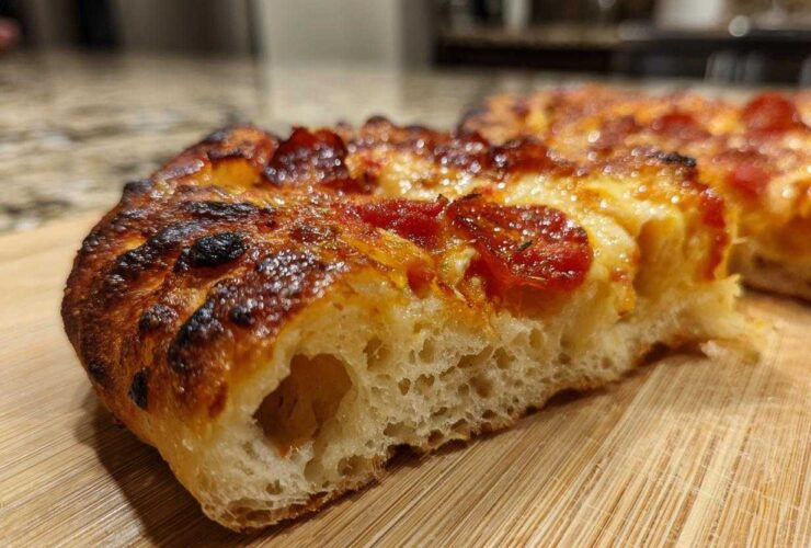 Close-up of a thick slice of pepperoni pizza showing the airy crumb structure of sourdough discard pizza dough.
