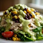 Close-up of a vibrant southwest chicken salad featuring shredded chicken, black beans, corn, and creamy green dressing.