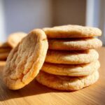 Close-up of a stack of soft, golden vegan sugar cookies coated in cinnamon sugar.