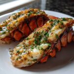 Two perfectly cooked Air Fryer Garlic Butter Lobster Tails, split and topped with melted butter and fresh parsley.