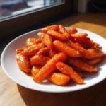 A white plate piled high with glossy Air Fryer Maple Glazed Carrots, glistening under natural light.
