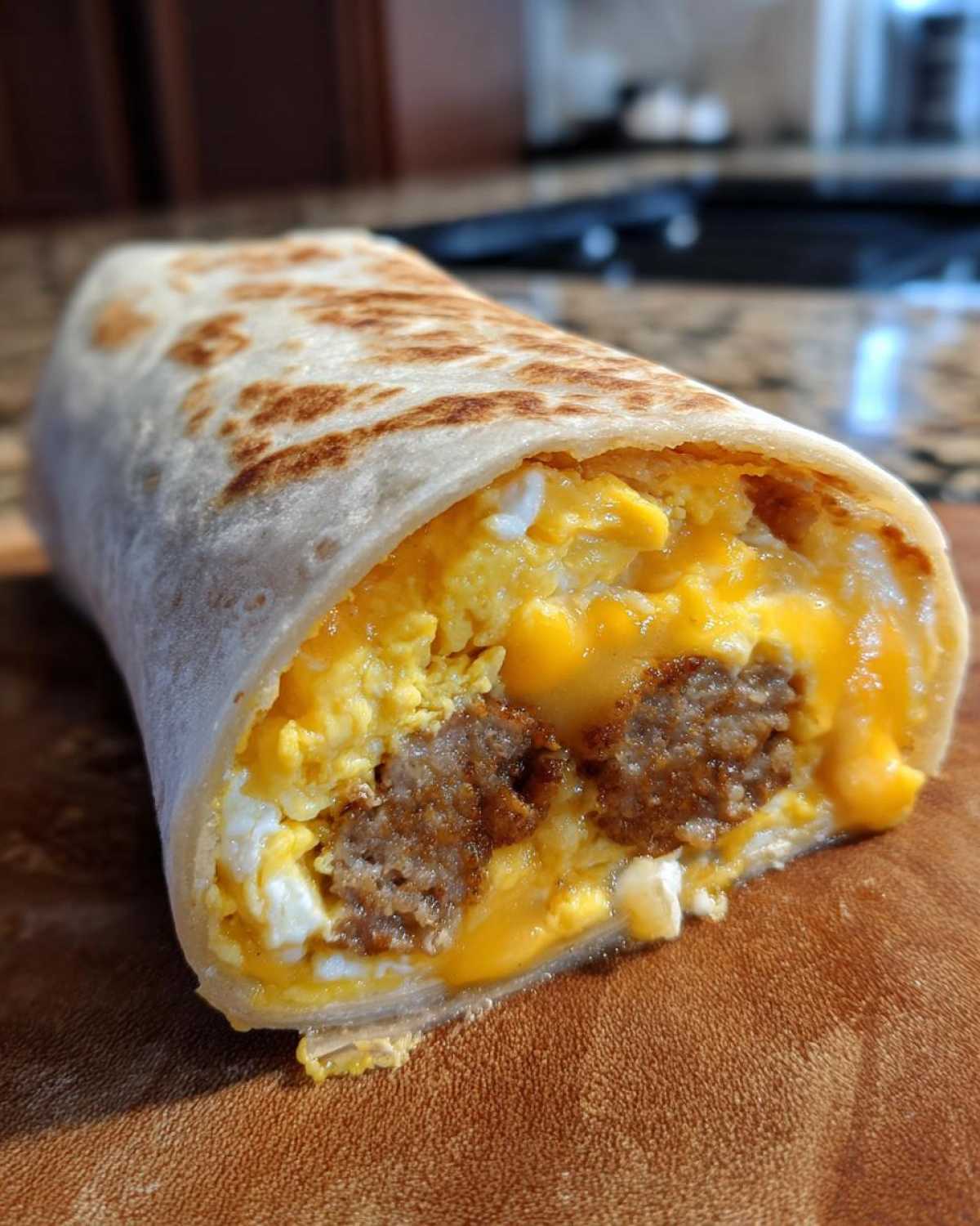 Cross-section view of a Copycat Dunkin' Wake-Up Wrap showing scrambled eggs, sausage, and melted cheese in a tortilla.