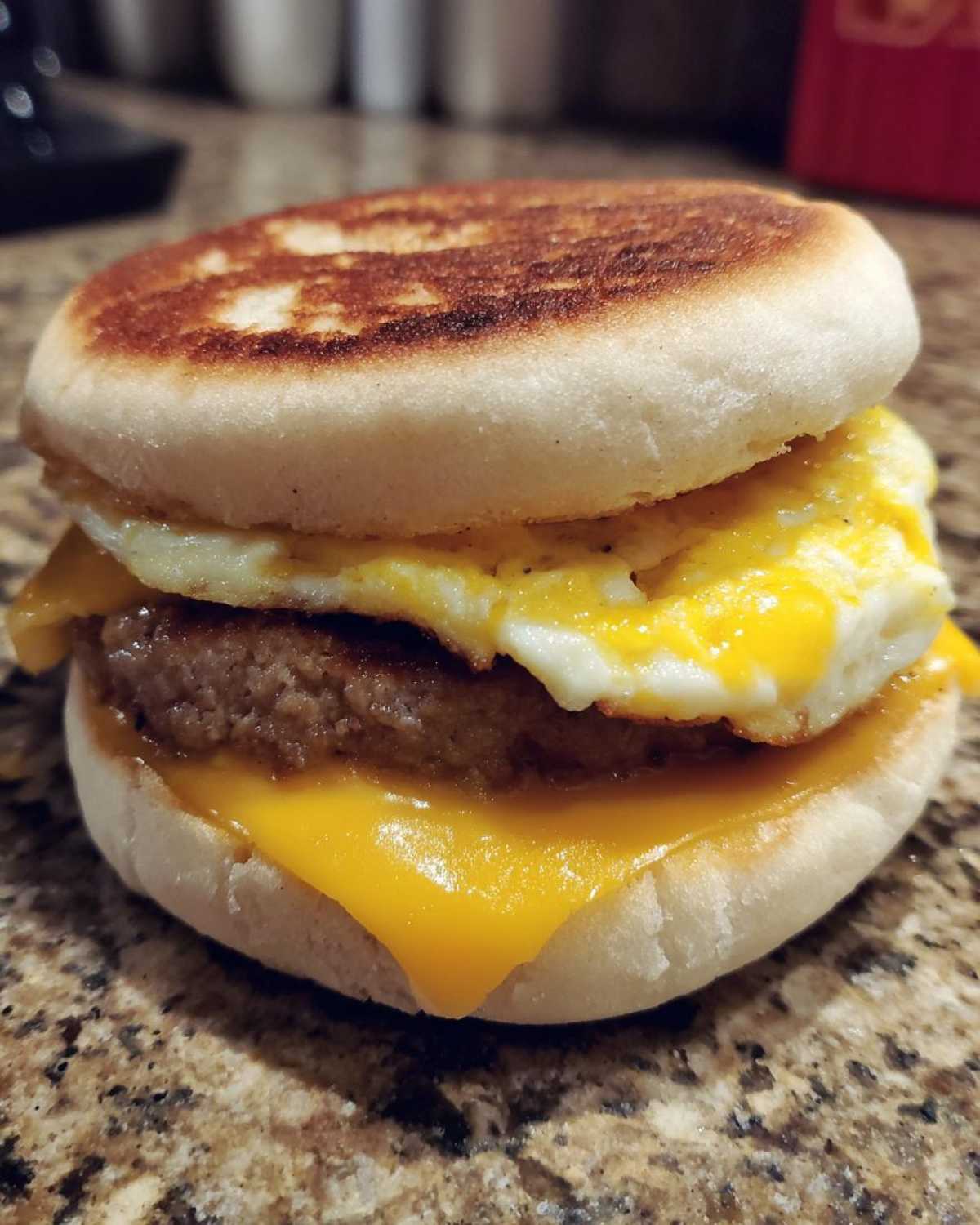 Close-up of a homemade Copycat McDonald's Sausage Egg McMuffin with toasted English muffin, sausage patty, egg, and melted cheese.