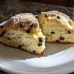 Two halves of a Gluten-Free Chocolate Chip Scone, showing a fluffy interior and sugar topping, served on a white plate.