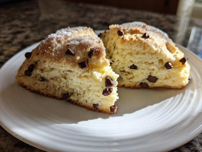 Two halves of a Gluten-Free Chocolate Chip Scone, showing a fluffy interior and sugar topping, served on a white plate.