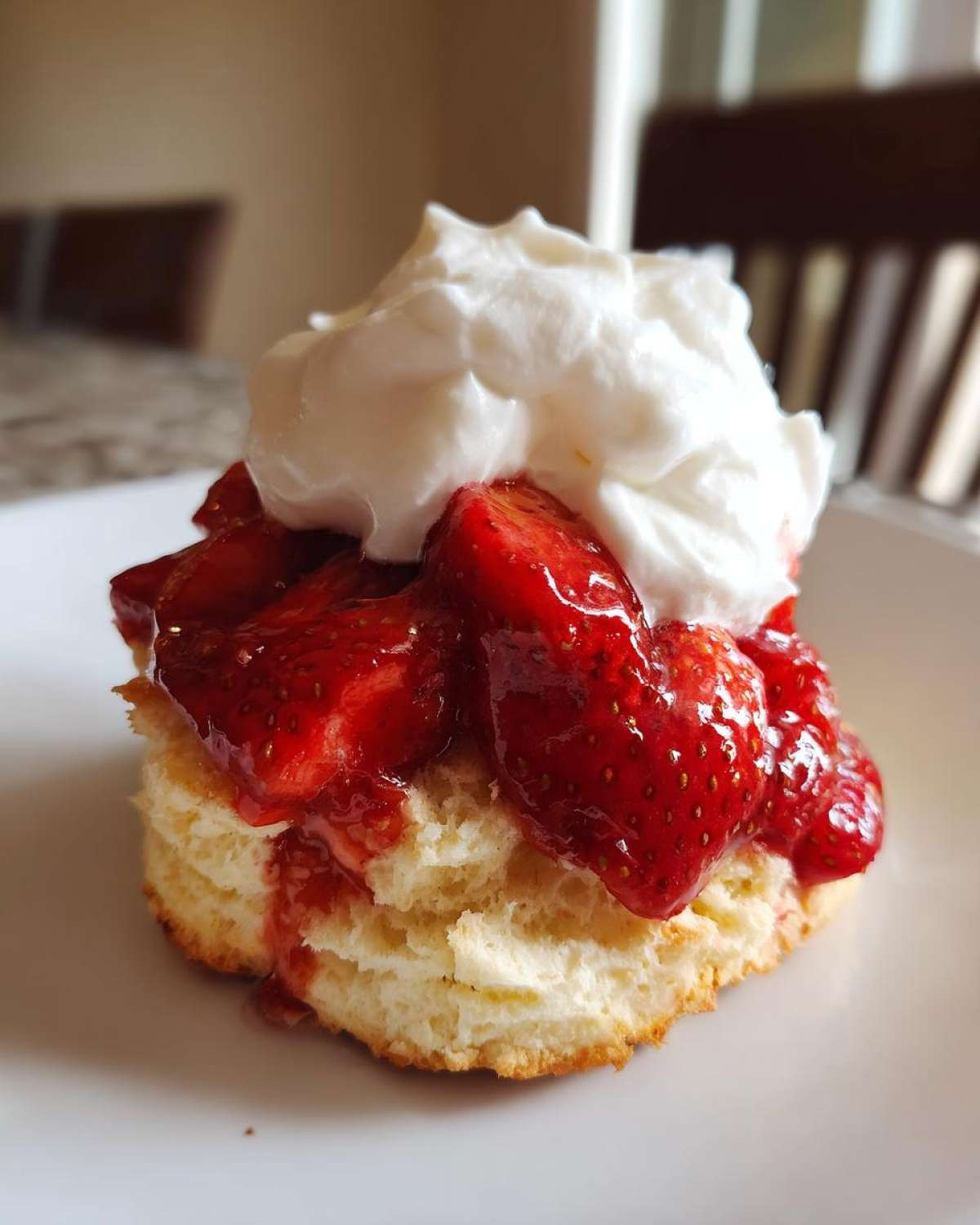 Close-up of a Gluten-Free Strawberry Shortcake Biscuits topped with macerated strawberries and whipped cream.