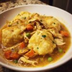 Close-up of creamy Instant Pot Chicken and Dumplings featuring tender chicken, carrots, peas, and fluffy dumplings.