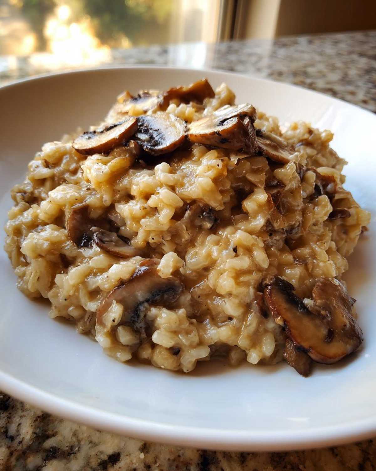 Close-up of rich Instant Pot Creamy Mushroom Risotto topped with sautéed mushroom slices in a white bowl.