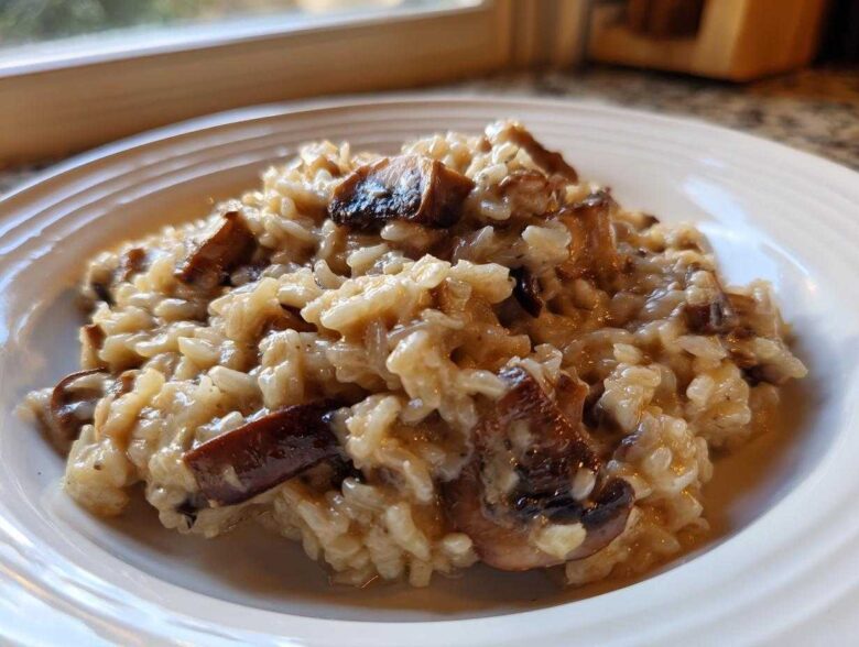 Close-up of creamy Instant Pot Creamy Mushroom Risotto with rich, browned mushroom pieces on a white plate.