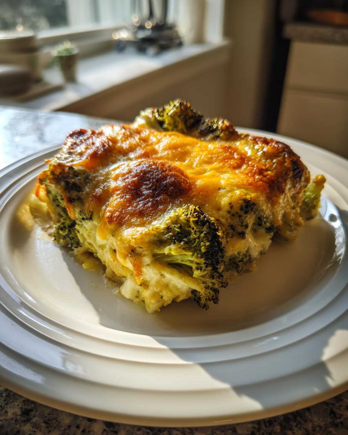 A square serving of Keto Cheesy Broccoli Casserole featuring bright green broccoli florets and a bubbly, golden-brown cheese topping.