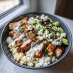 Close-up of Keto Greek Chicken Bowls with Tzatziki, featuring grilled chicken, cauliflower rice, feta, and cucumbers.