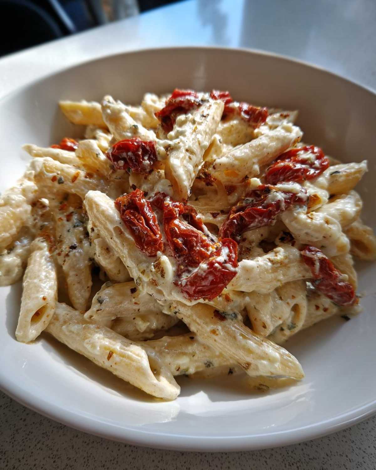 Close-up of One-Pot Creamy Goat Cheese Pasta with roasted tomatoes and herbs in a white bowl.