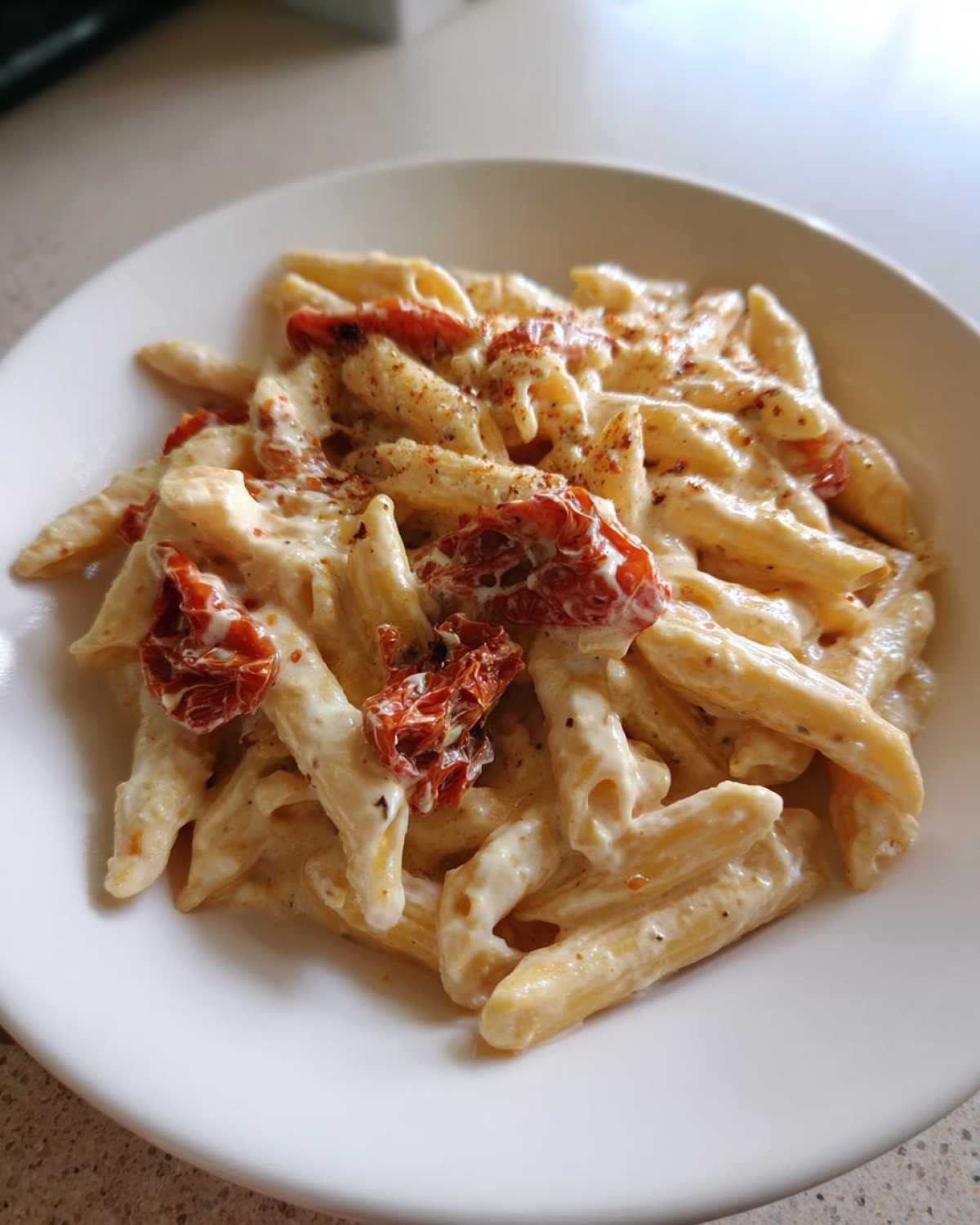 Close-up of One-Pot Creamy Goat Cheese Pasta with penne coated in a rich sauce and topped with roasted tomatoes.