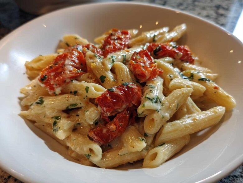 Close-up of One-Pot Creamy Goat Cheese Pasta with penne, creamy sauce, and roasted red tomatoes.