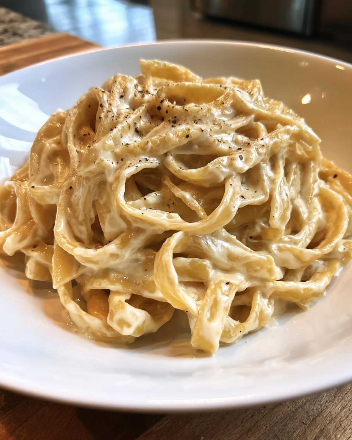 Close-up of fettuccine pasta coated in rich Vegan Creamy Cashew Alfredo Sauce and topped with black pepper.