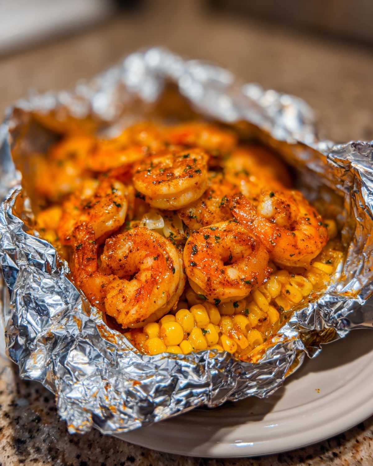 Close-up of seasoned shrimp and corn cooked inside a foil packet, part of the Sheet Pan Cajun Shrimp and Corn Foil Packets recipe.