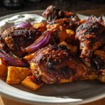 Plated Sheet Pan Harissa Chicken with Sweet Potatoes, red onion wedges, and a side of yogurt sauce.