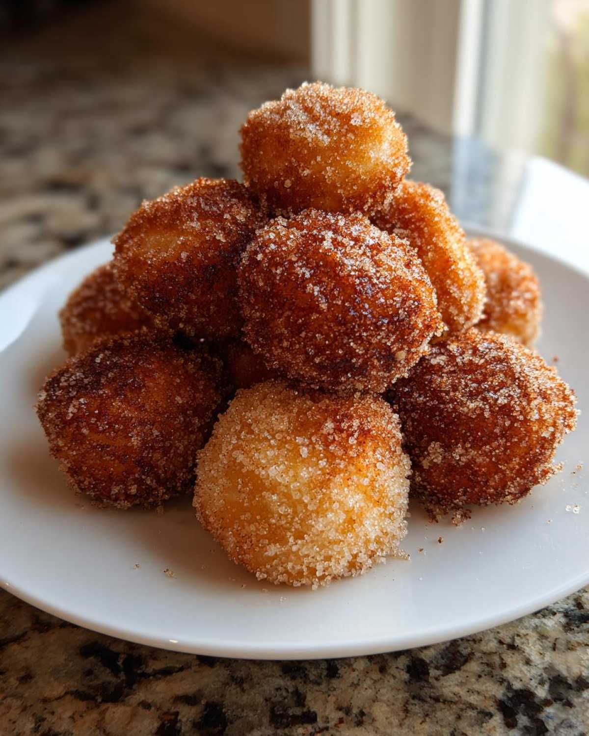 A stack of golden brown Air Fryer Crispy Cinnamon Sugar Biscuit Bites coated heavily in sparkling cinnamon sugar.