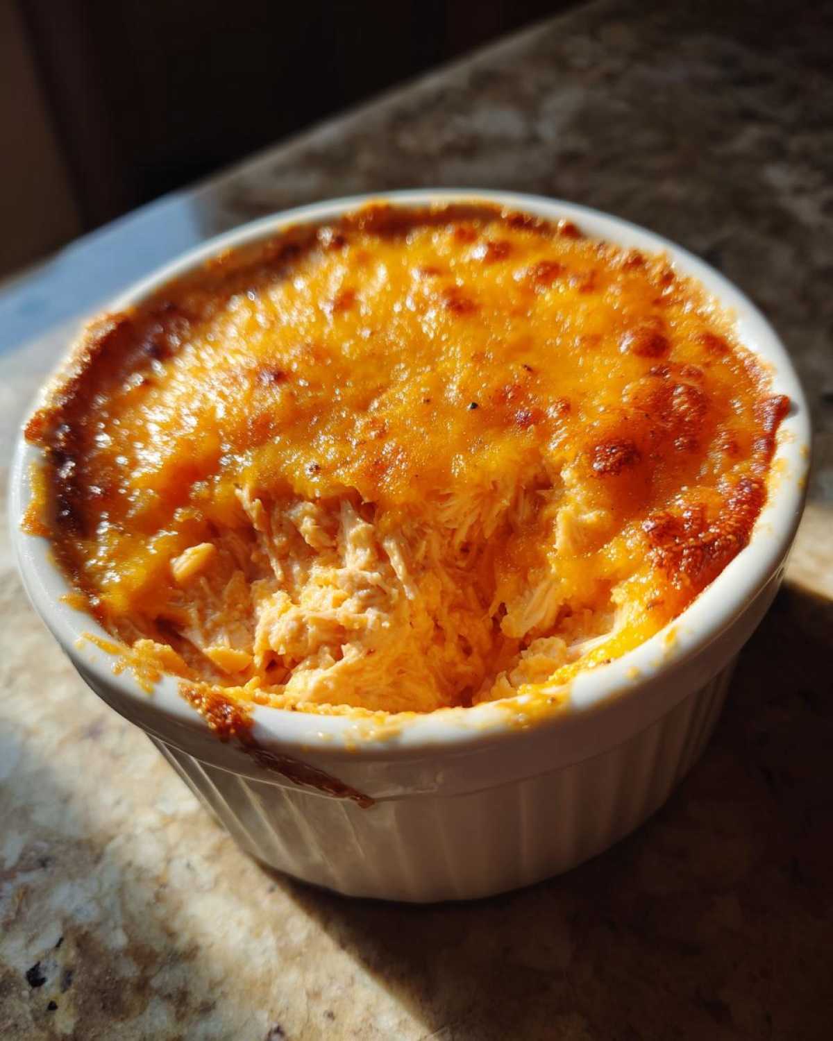 Close-up of hot, cheesy cottage cheese buffalo chicken dip baked until bubbly in a white ramekin.