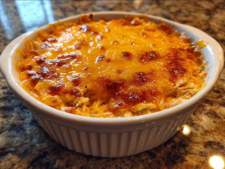 Close-up of hot, bubbly cottage cheese buffalo chicken dip topped with melted, browned cheddar cheese in a white ramekin.