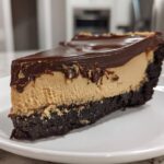 A thick slice of chocolate peanut butter pie with a dark crust, creamy peanut butter filling, and glossy chocolate topping.