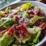 Close-up of a vibrant grinder salad featuring crisp lettuce, slices of cured meat, and grated Parmesan cheese.