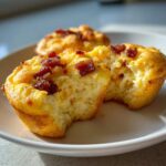Close-up of two Copycat Café-Style Bacon Gruyere Egg Bites on a white plate, one with a bite taken out.