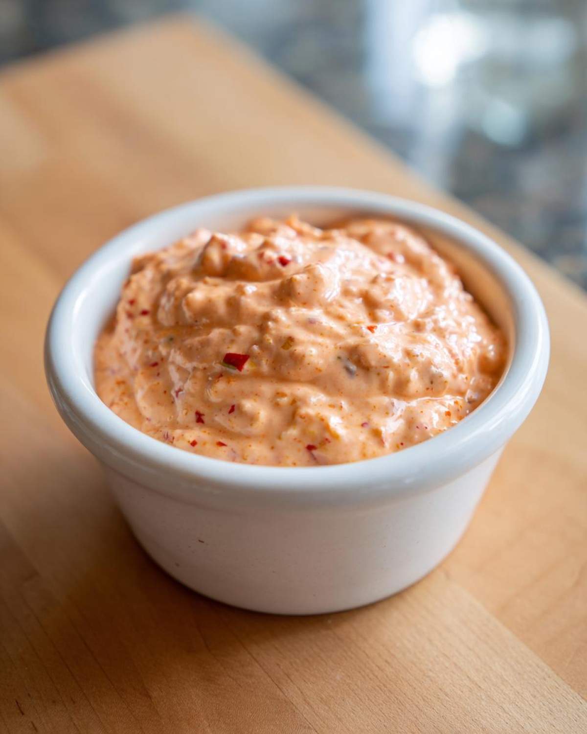 A close-up of thick, orange-pink Copycat Classic Burger Spread Sauce with visible red flecks in a small white bowl.
