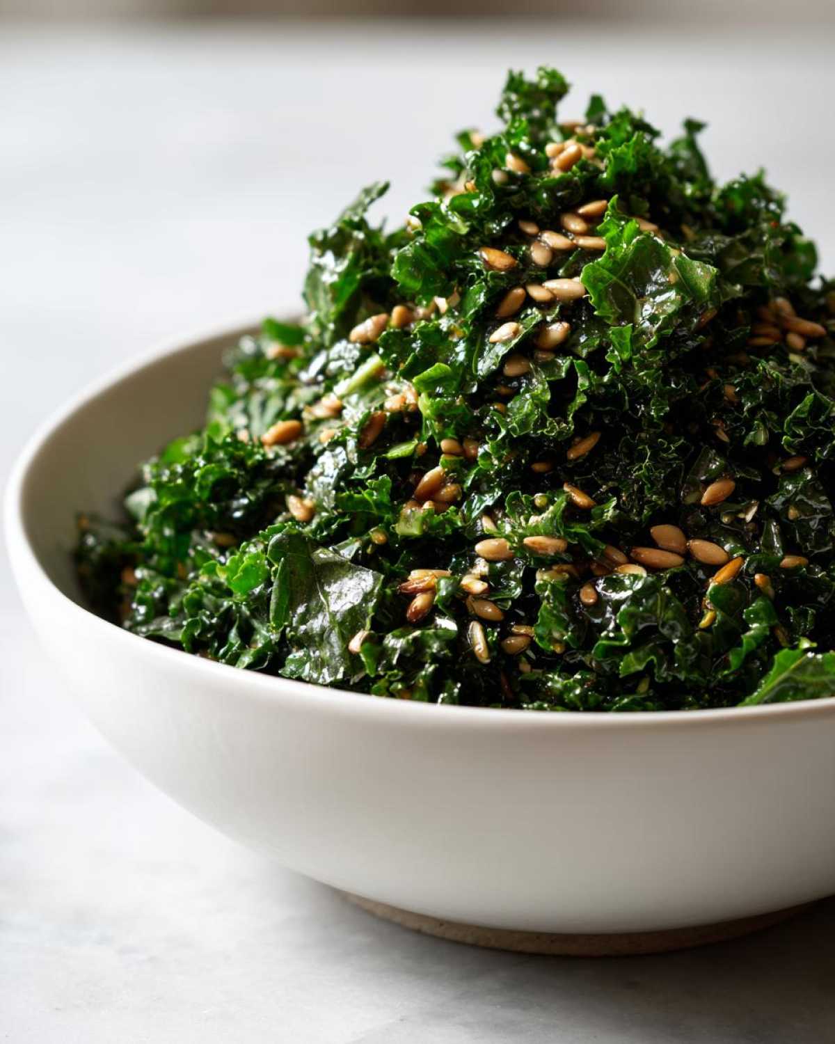 A close-up of massaged kale topped with seeds, representing the Copycat Kale Crunch Salad.