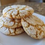 A stack of four Crackly Sugar Cookies With Rich Toffee Bits Inside resting on a white plate.