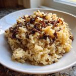 A close-up of a white bowl filled with creamy French Onion Butter Rice topped with crispy caramelized onions.