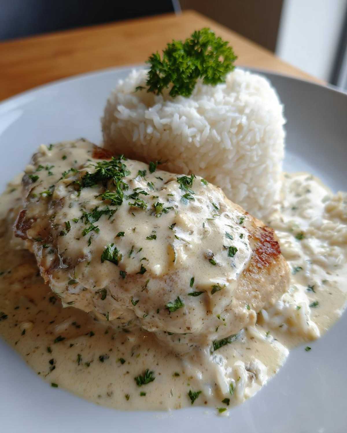A perfectly plated serving of Creamy Smothered Chicken and Rice, topped with parsley.