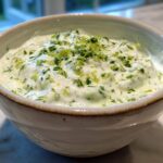 Close-up of Easy 5-Minute Salsa Verde Yogurt Dip topped with fresh herbs and lime zest in a rustic bowl.