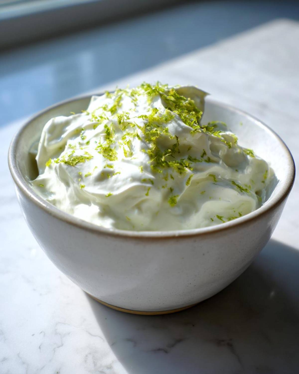 Close-up of a creamy white dip topped with bright green lime zest, likely the Easy 5-Minute Salsa Verde Yogurt Dip.