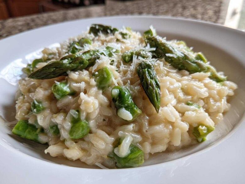 Close-up of Easy Creamy Asparagus Risotto topped with fresh asparagus spears and grated Parmesan.