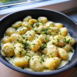 Close-up of Easy One-Pan Creamy Garlic Butter Gnocchi coated in a rich, pale sauce and topped with fresh parsley.