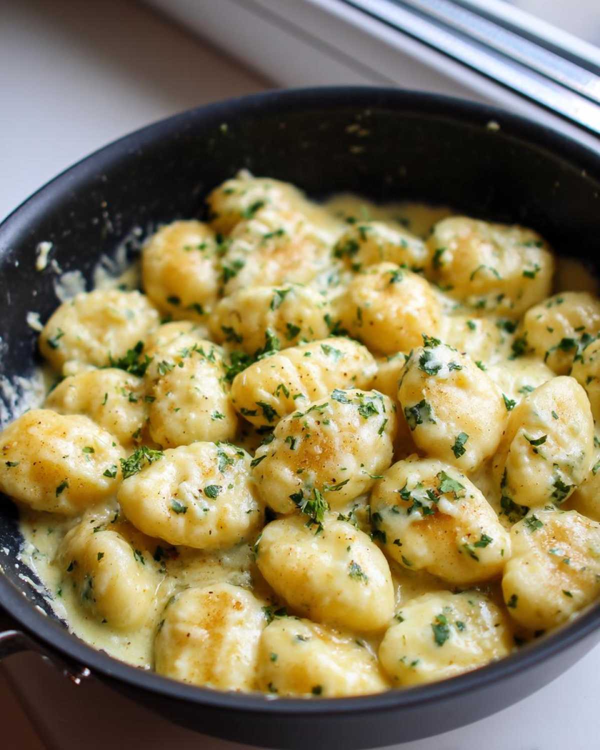 Close-up of Easy One-Pan Creamy Garlic Butter Gnocchi coated in a rich sauce and topped with fresh parsley.