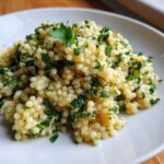 Close-up of fluffy couscous mixed with fresh green herbs, ready to eat, featuring Easy One-Pot Creamy Lemon Herb Couscous.