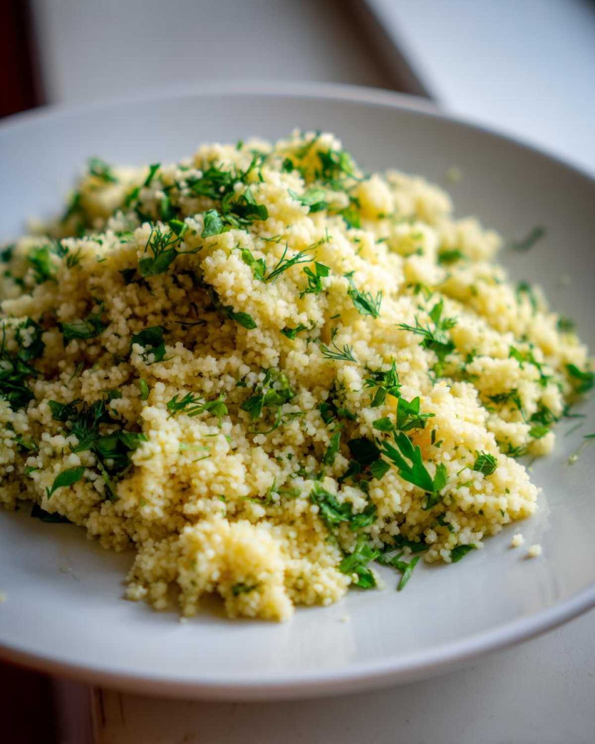 A close-up of fluffy Easy One-Pot Creamy Lemon Herb Couscous topped generously with fresh chopped parsley and dill.